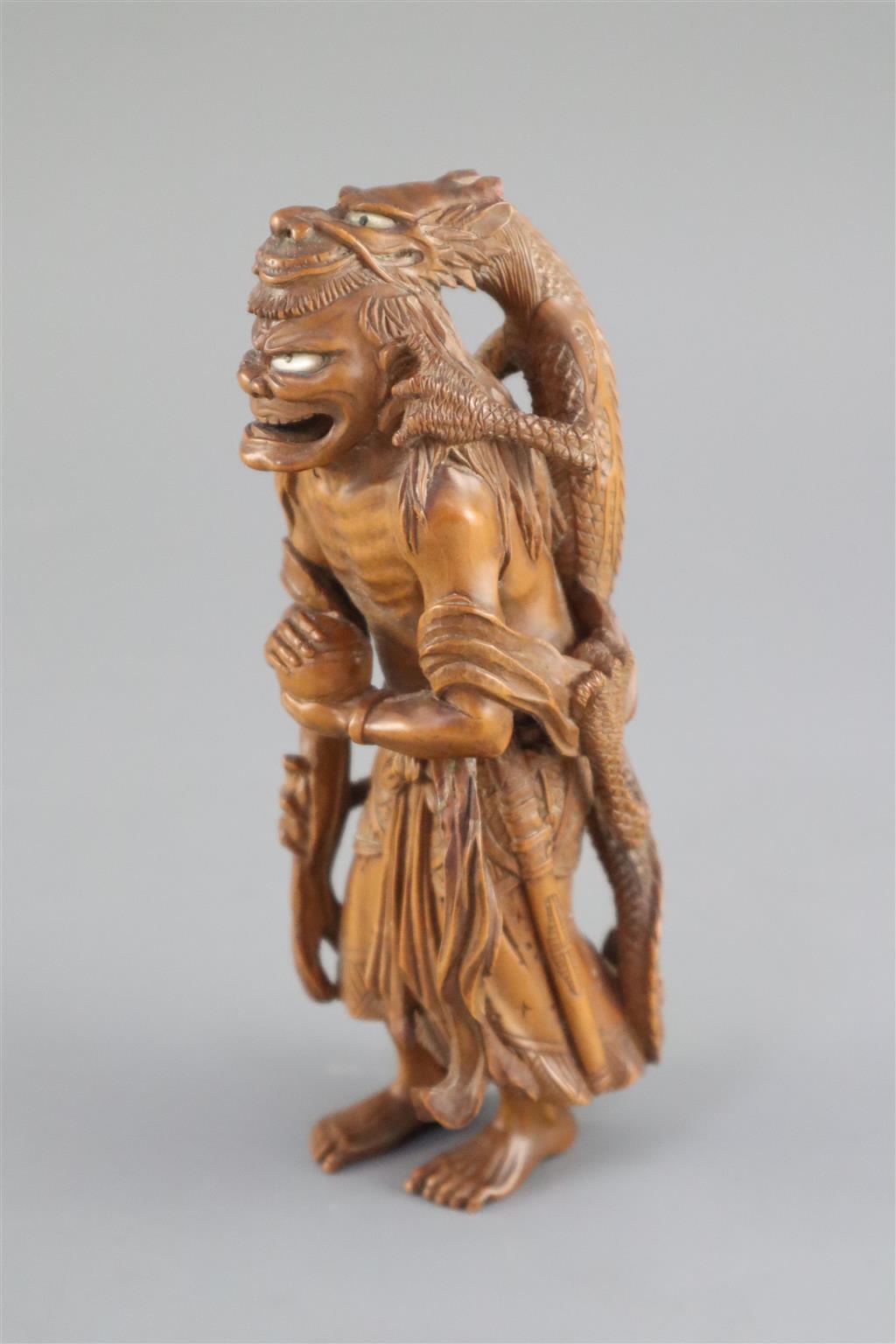 A fine Japanese boxwood okimono of the Sennin Handaka Sonja with a dragon clambering on his back, 19th century, signed Masakazu, 16.5cm